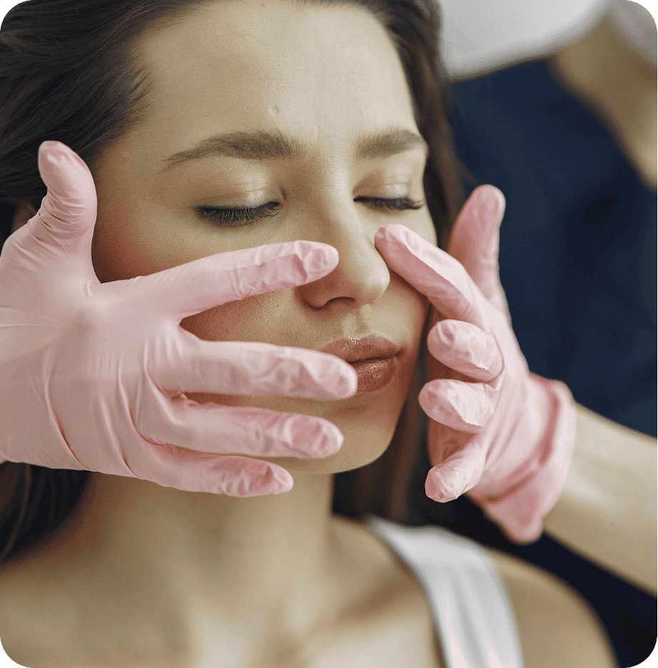 A woman with closed eyes receives a relaxing facial massage from hands wearing pink gloves, as part of a comprehensive primary care routine.