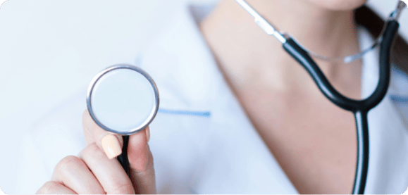 Close-up of a person wearing a white coat and holding a stethoscope, ready to perform a primary care medical examination.